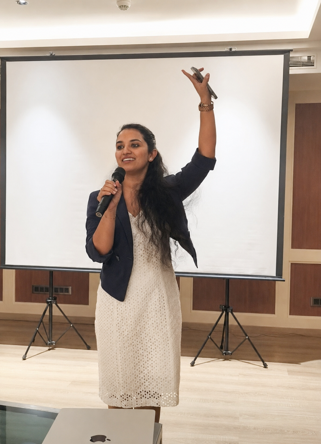Anjaly Warrier speaking on stage with microphone raised